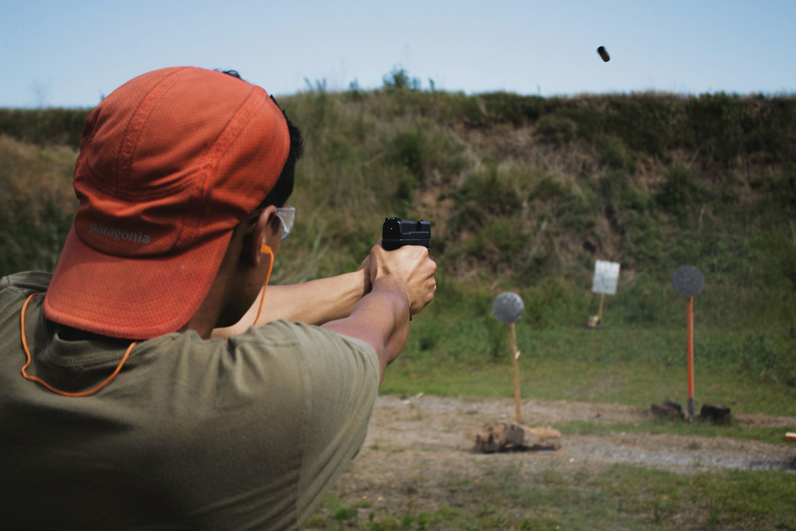 Shooter at an outdoor range with proper eye and ear protection